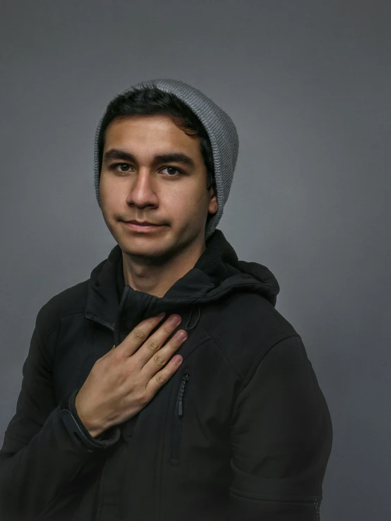 a man in black hoodie with his hands in his chest