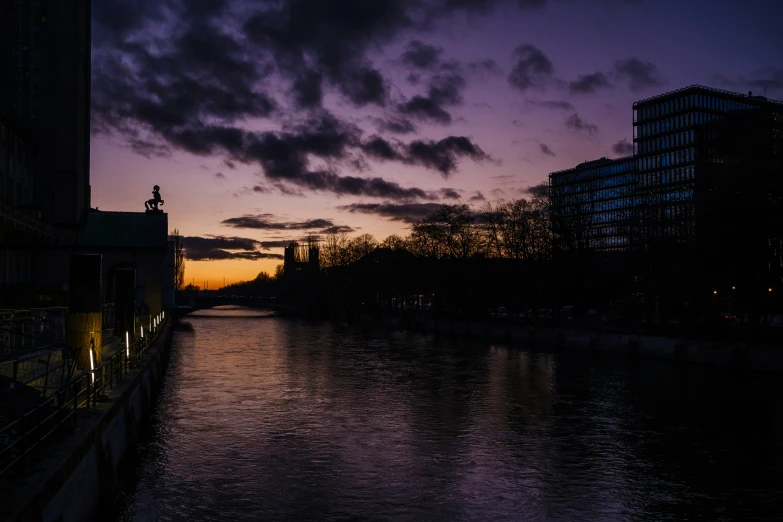 a sunset is seen behind the water and buildings