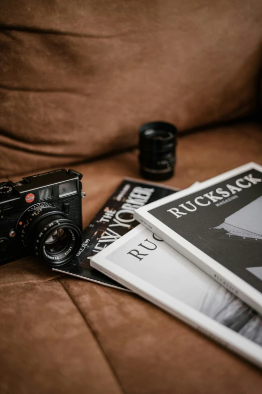 a brown couch with some books and a camera on it