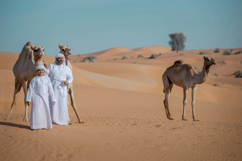 a couple of men and women are standing around three camels