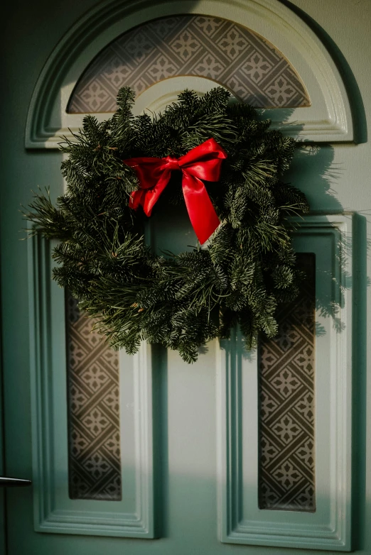 a wreath and bow hanging on the side of a blue door