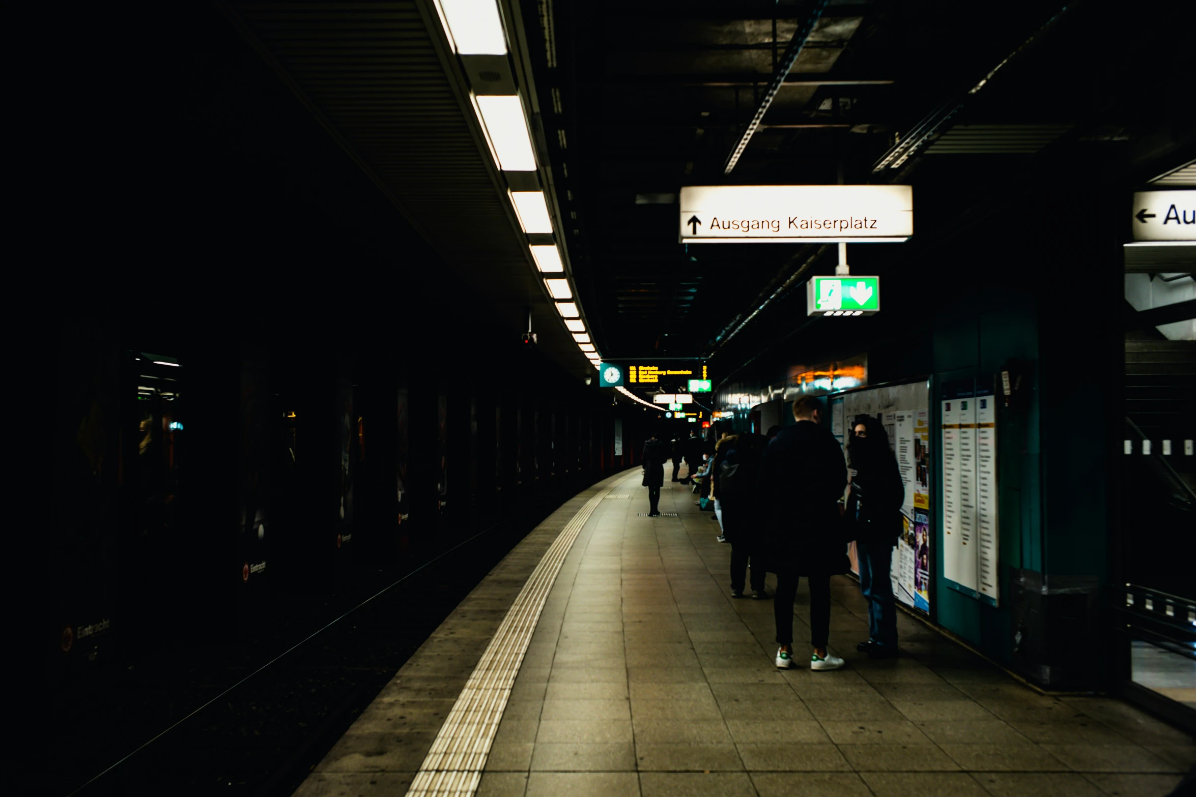 people walking and standing at a subway station at night