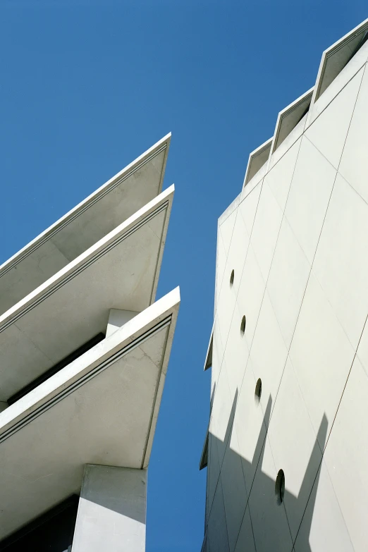 two grey and white buildings against a blue sky