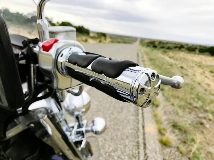 the handlebars of a motorcycle with a road in the background