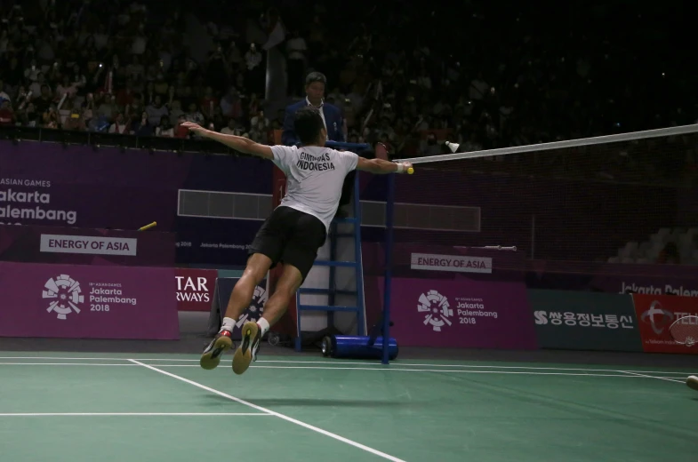 an asian man is playing tennis on a court