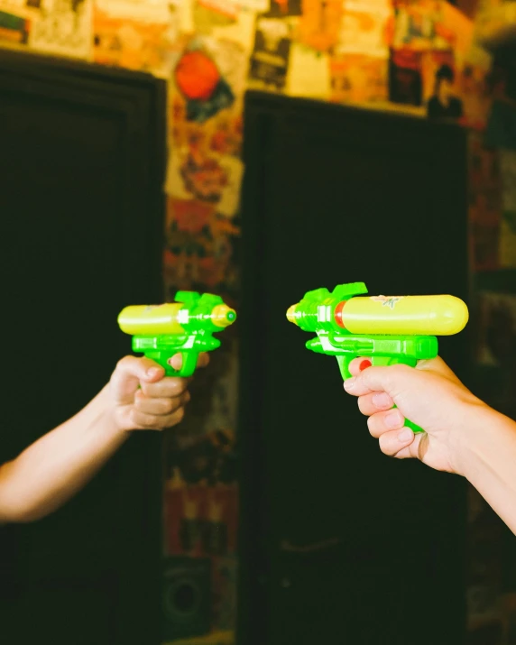 a person holding two green toy guns to the camera