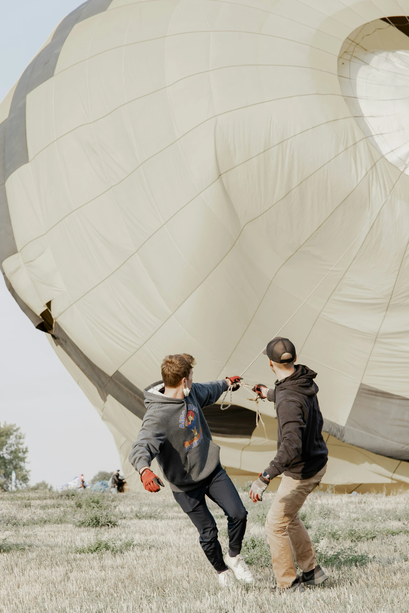 a couple of people standing in the grass near a large  air balloon