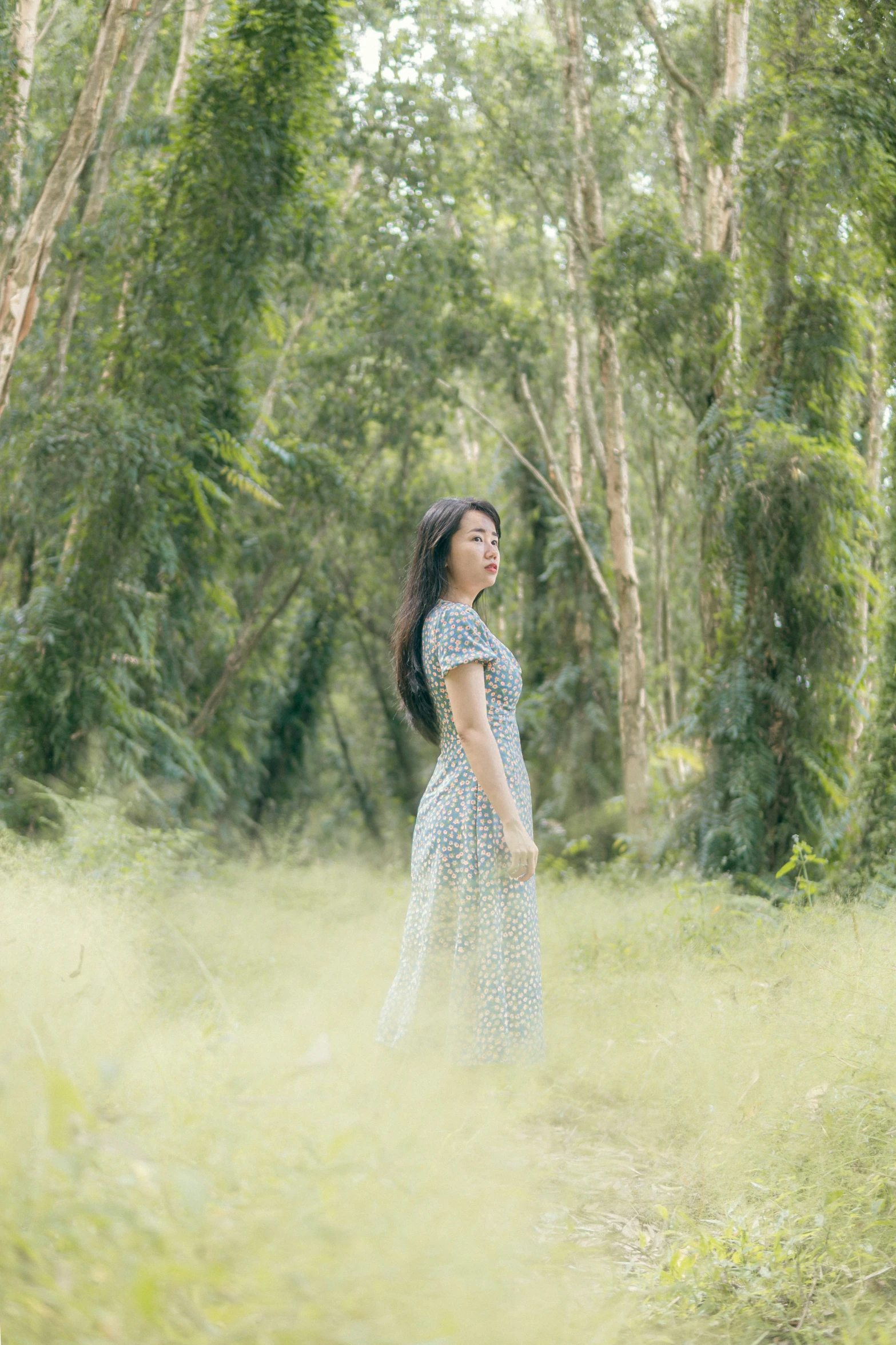 a woman standing in a field with her head turned to the side