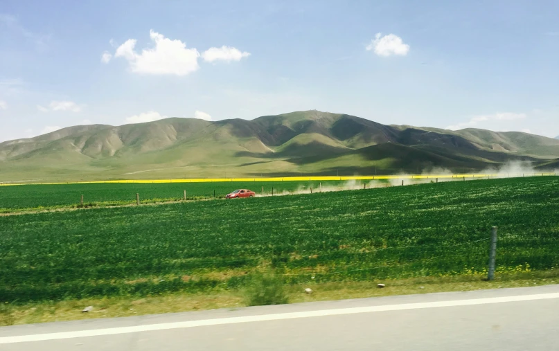 a car is driving down the road through an empty field