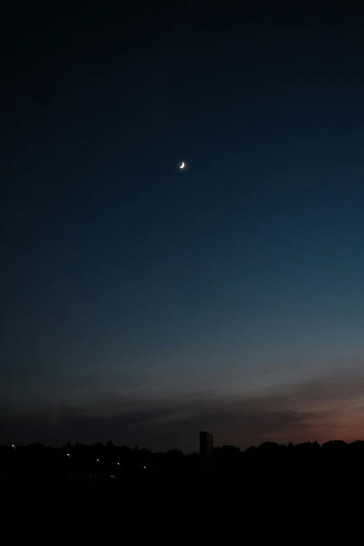 the moon is shining over a town during the day