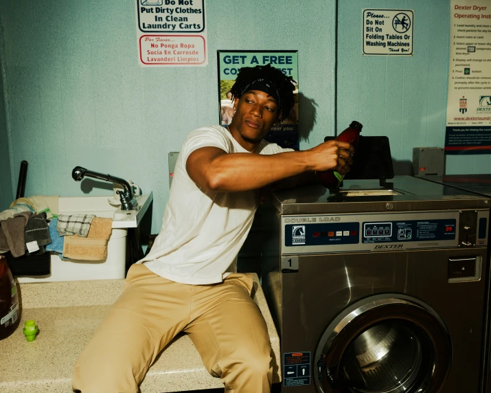 a man sitting on the edge of a washer with his arm out