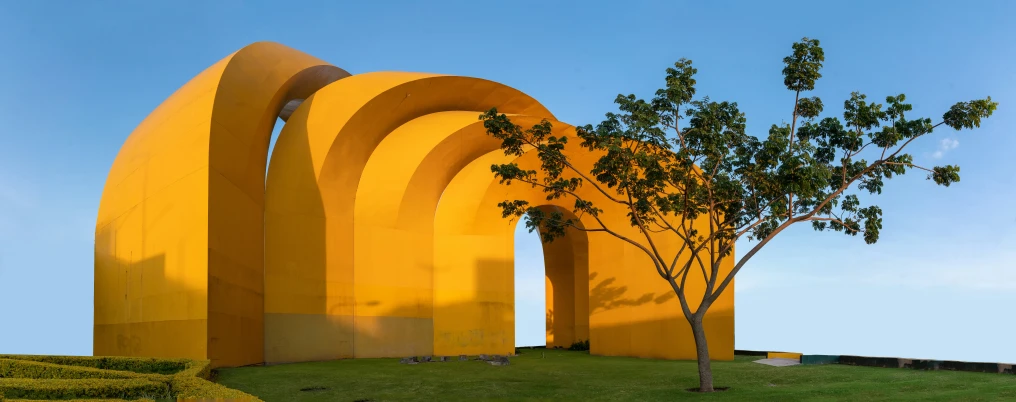 a large sculpture is on a hill by trees