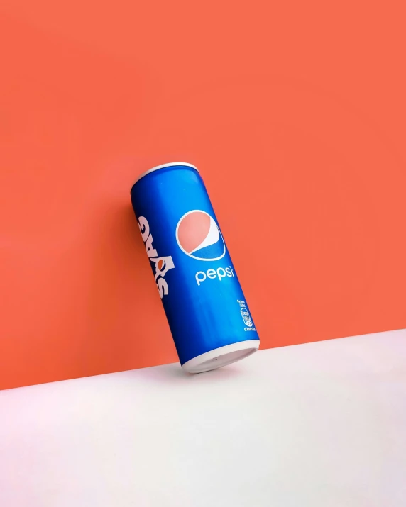 a soda can on a counter against an orange wall