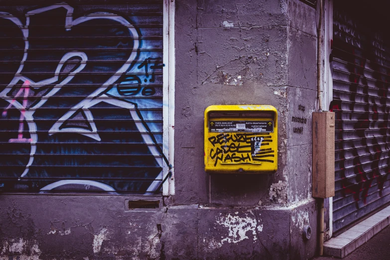 a yellow box with graffiti on it in front of a building