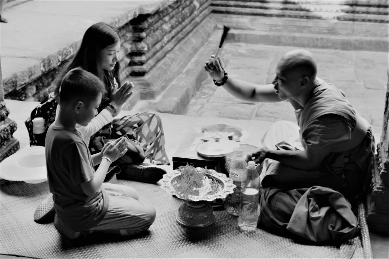 some people sitting down and eating while one person holds an object