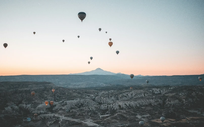  air balloons are flying above a mountain