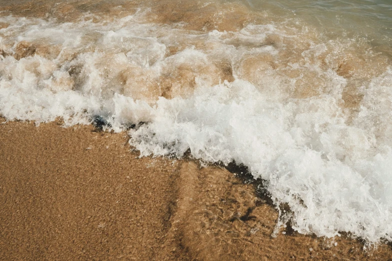 the ocean waves break into a brown sandy beach