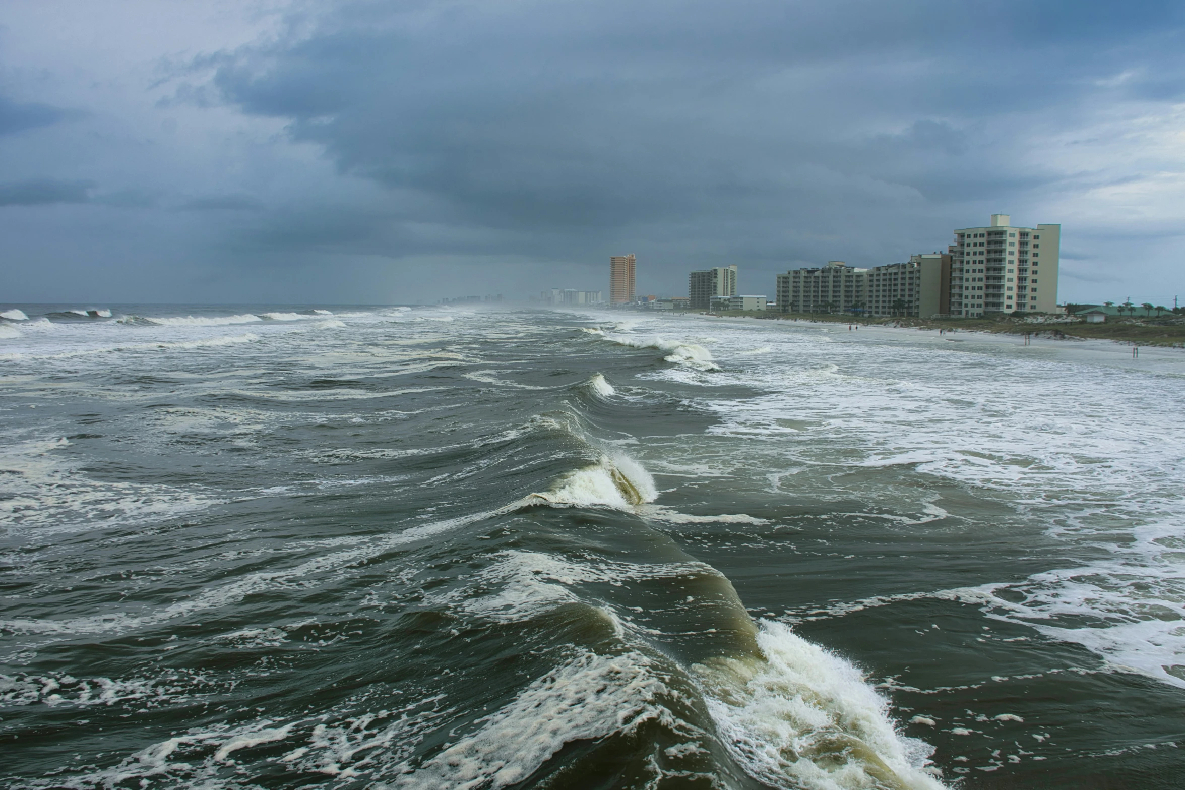 ocean waves come towards beach while a building stands in the background