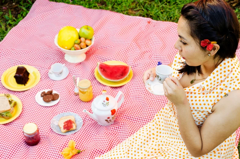 a woman sitting at a picnic table drinking from a cup