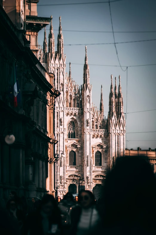 the people are walking next to the very tall building