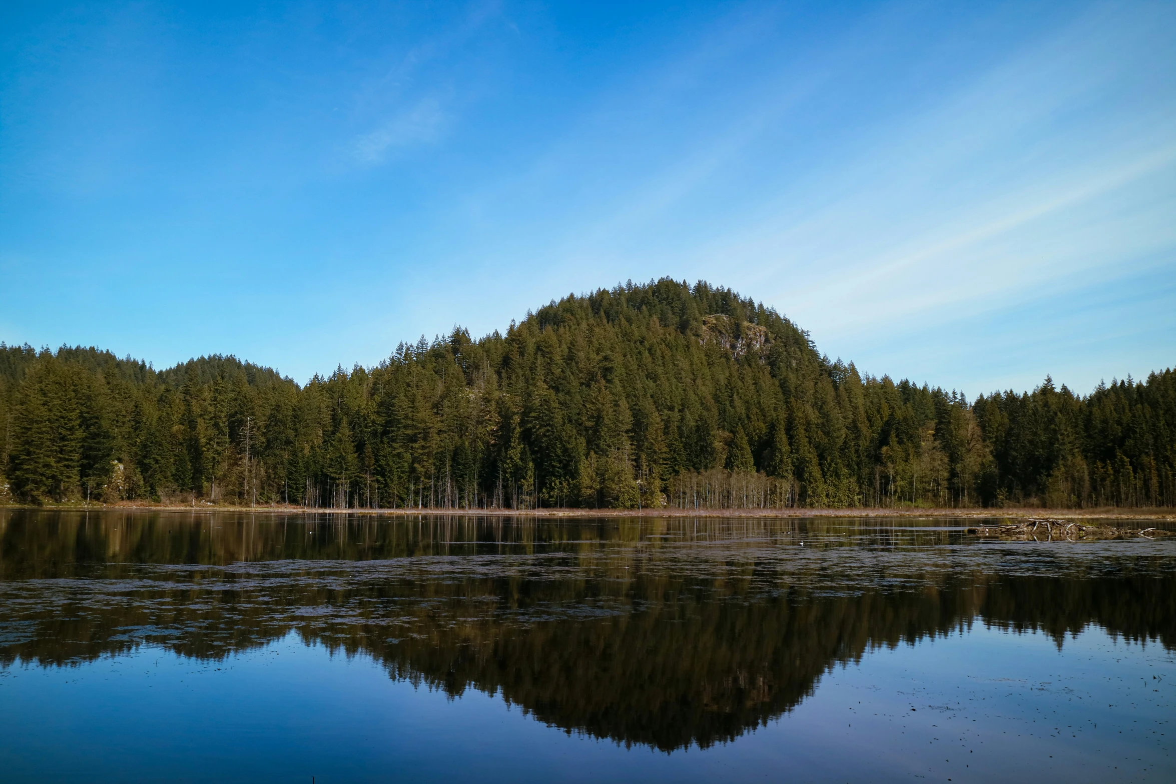 a large mountain next to water and trees