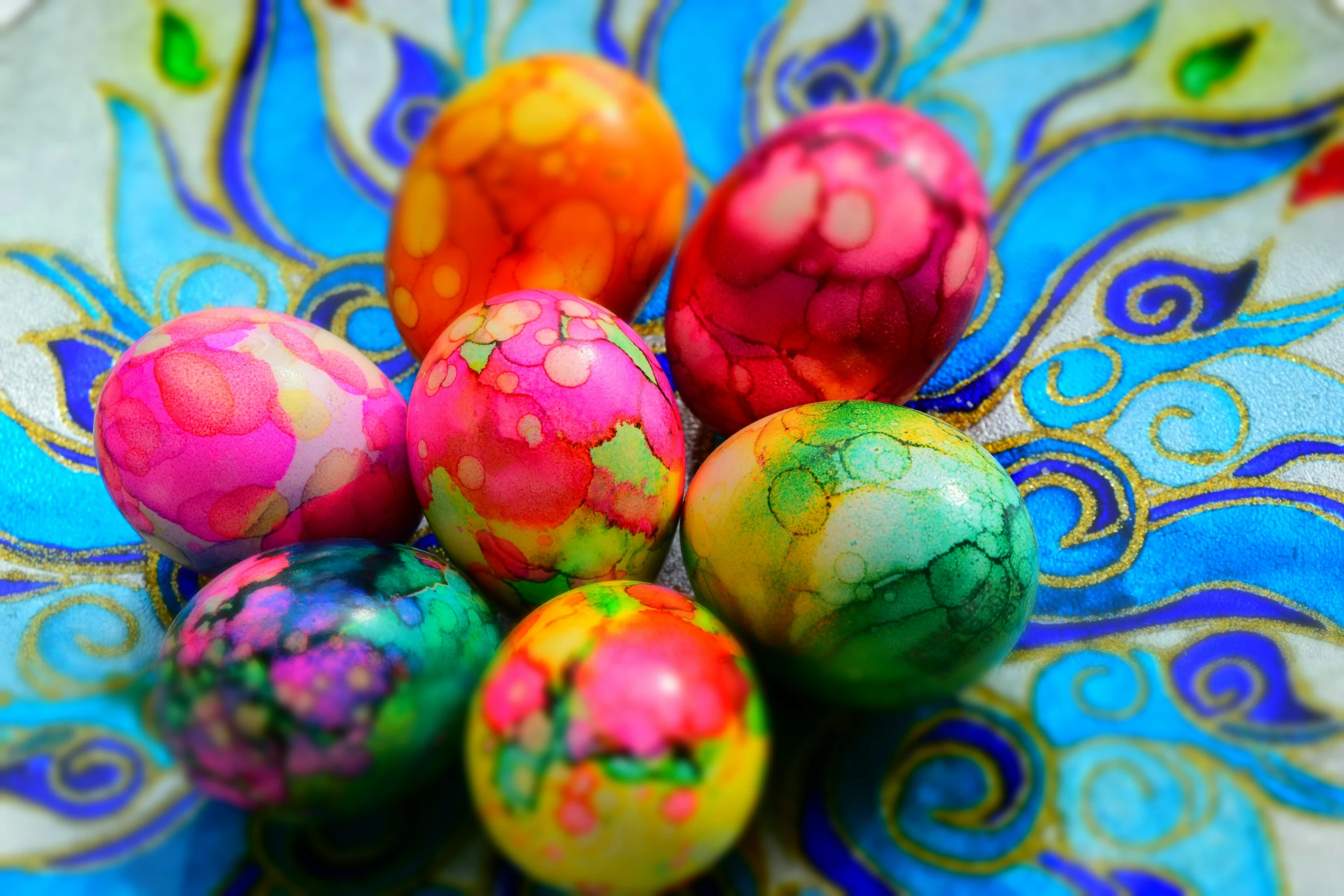 a bunch of colored eggs sit in a colorful bowl