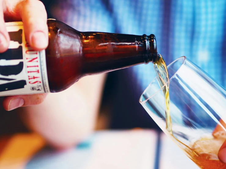 the man is pouring beer into the glass