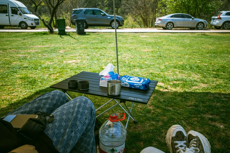 someone is sitting on the grass while having drinks and water