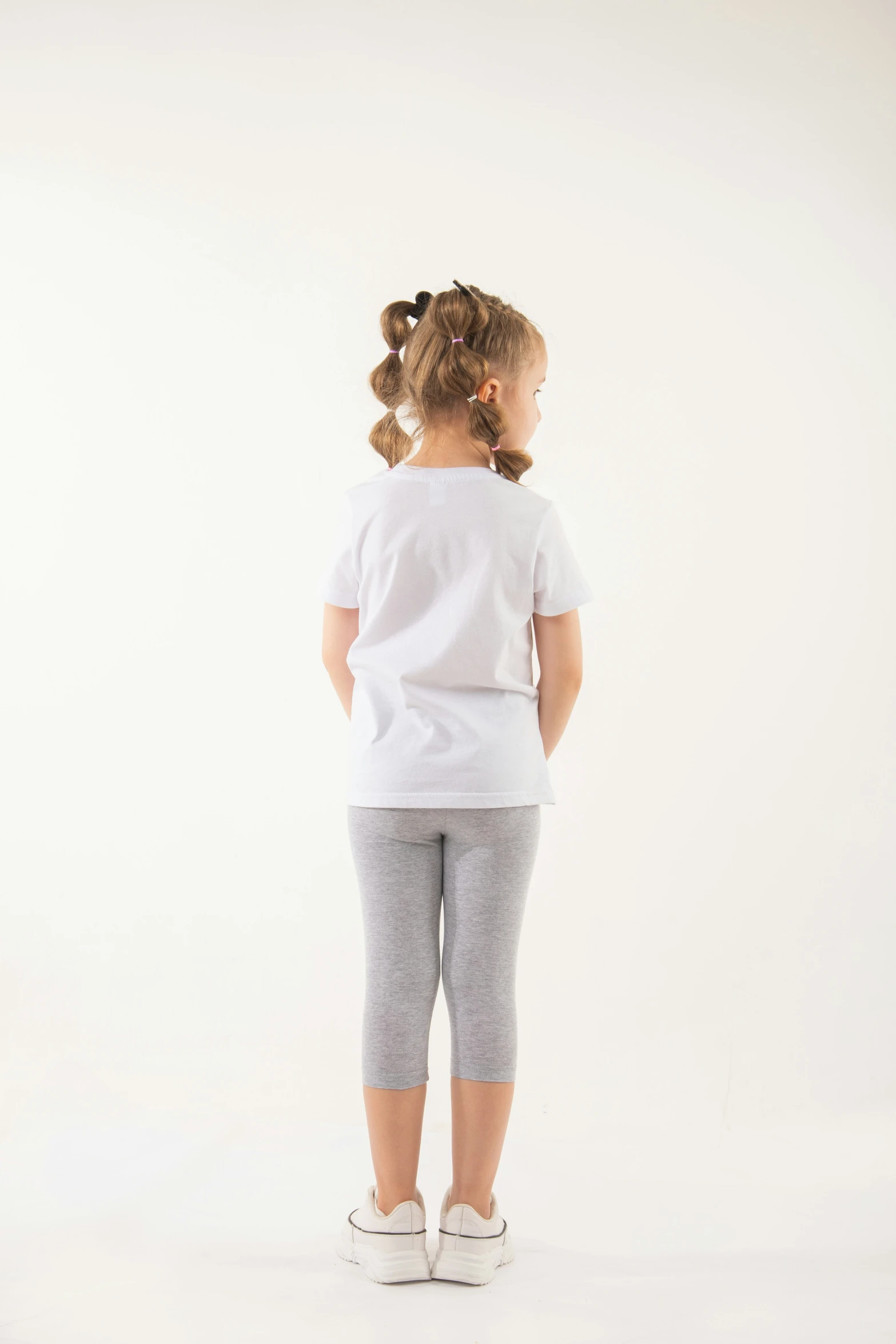 a  with a white tee and gray tights is facing away from the camera