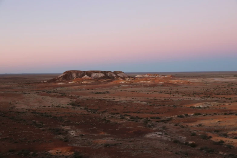 a desert scene with a lone horse standing on top