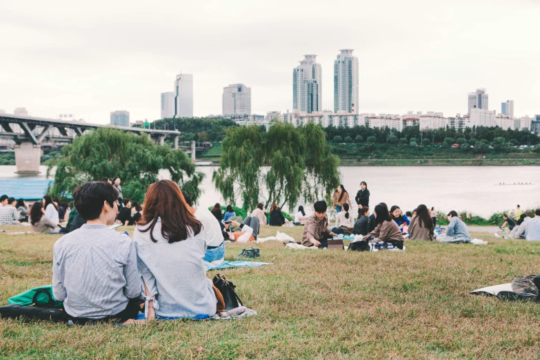 a group of people sitting by a river on picnicking