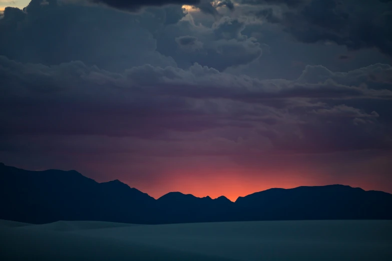 an expanse with mountains in the background at sunset