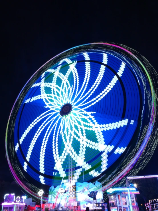 a colorful, spinning carnival ride is seen during a nighttime
