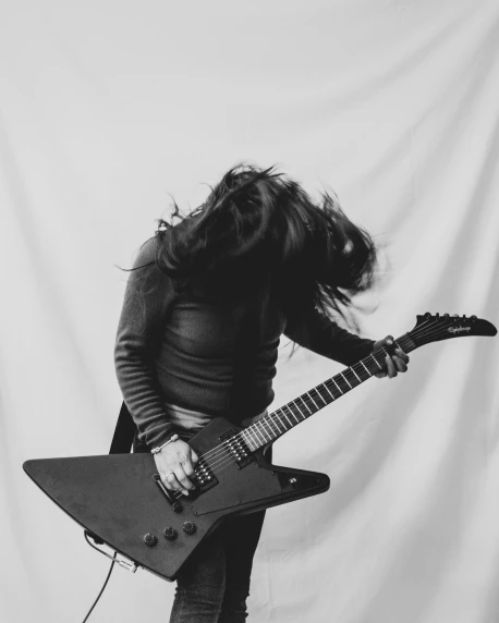 a woman with long hair standing next to a guitar