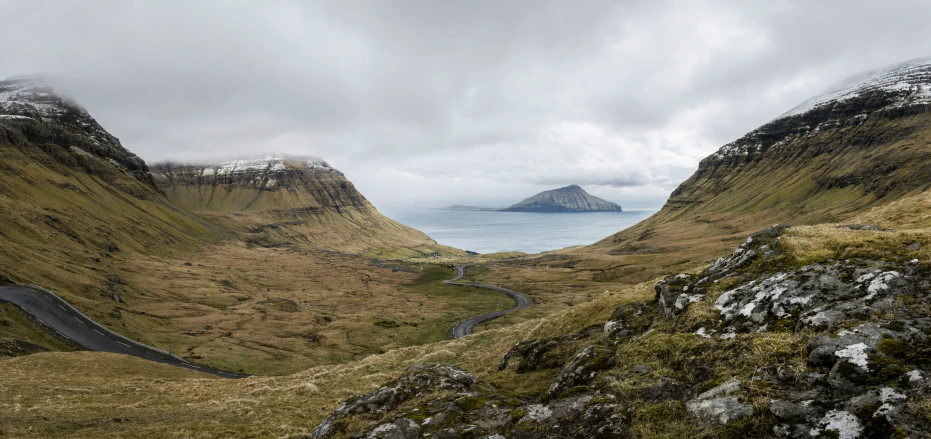 a mountain range with grass and some cliffs with a river in it