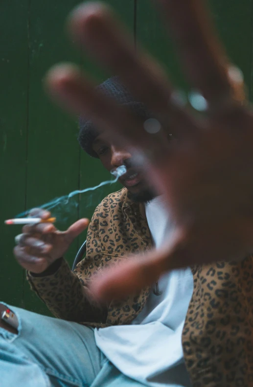 a man sitting down with a cigarette in his mouth