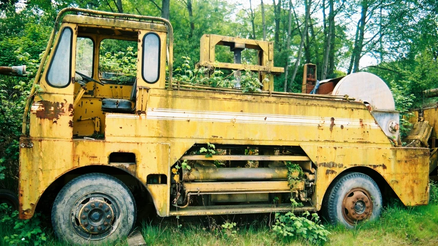 an old yellow truck sits parked in a field