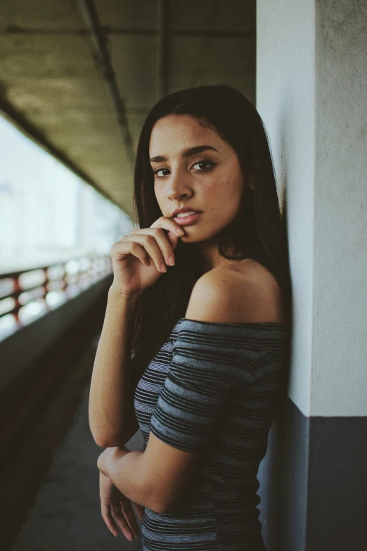 a woman leaning up against a wall by a train track