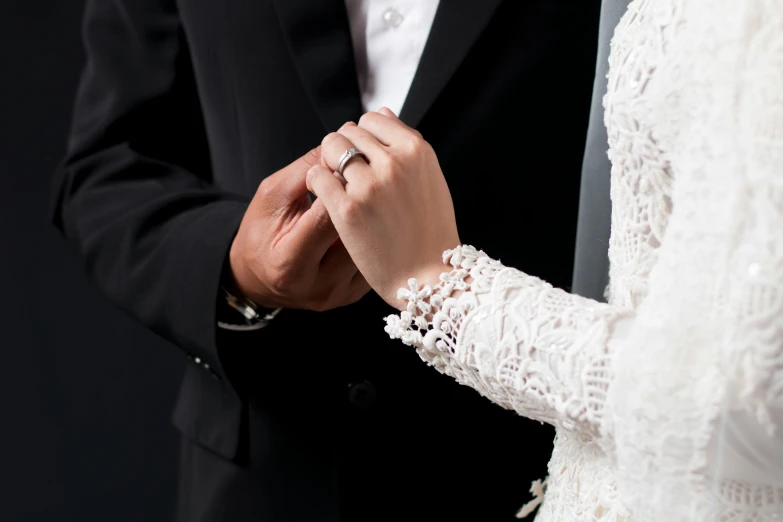 a man and woman with wedding rings holding hands