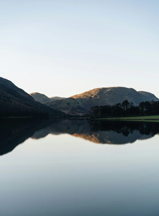 a calm mountain lake and a green hillside