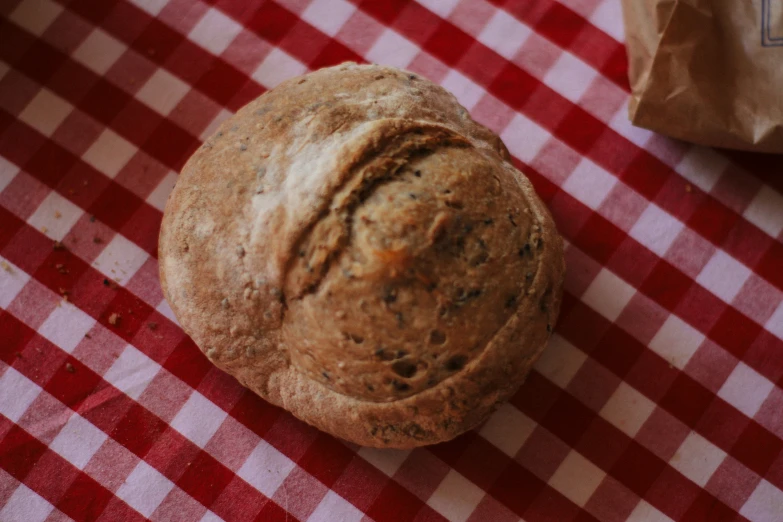 a muffin sitting on a table with a bag of brown stuff nearby