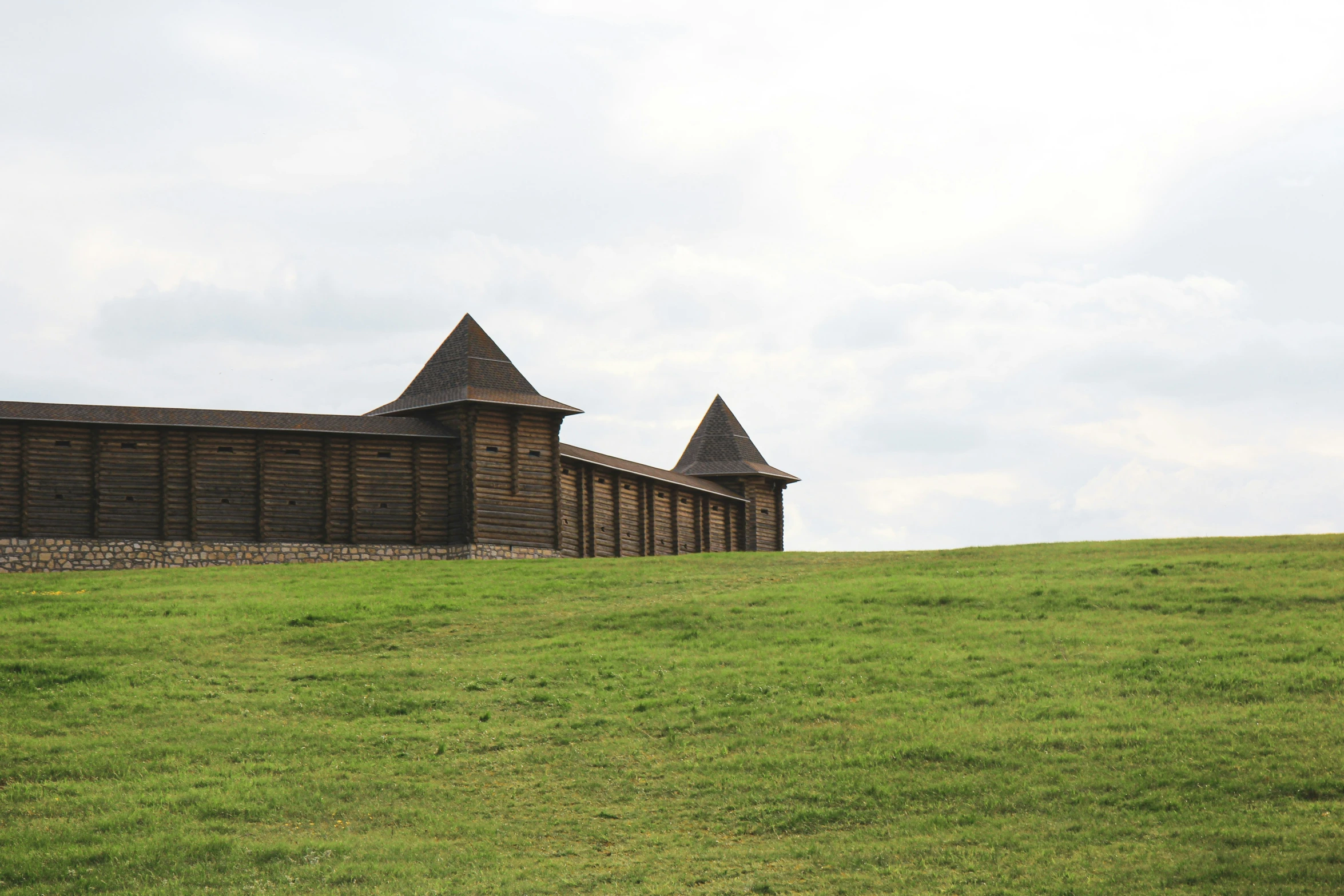 there is a fence on the hill by the wall