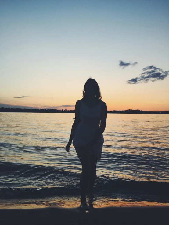 a person is walking on the beach at sunset