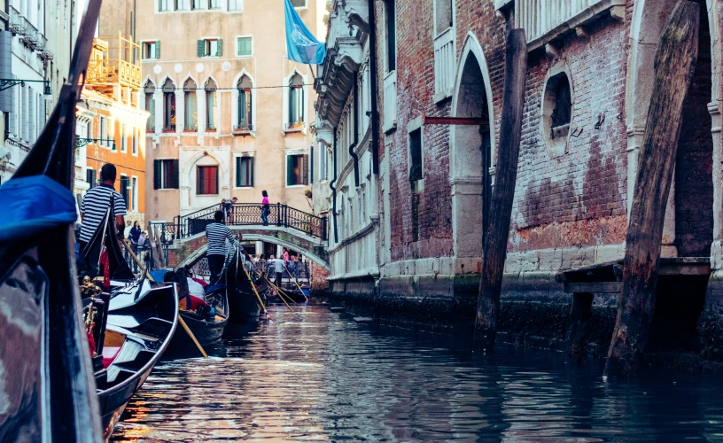 some gondolas line up along the side of a canal