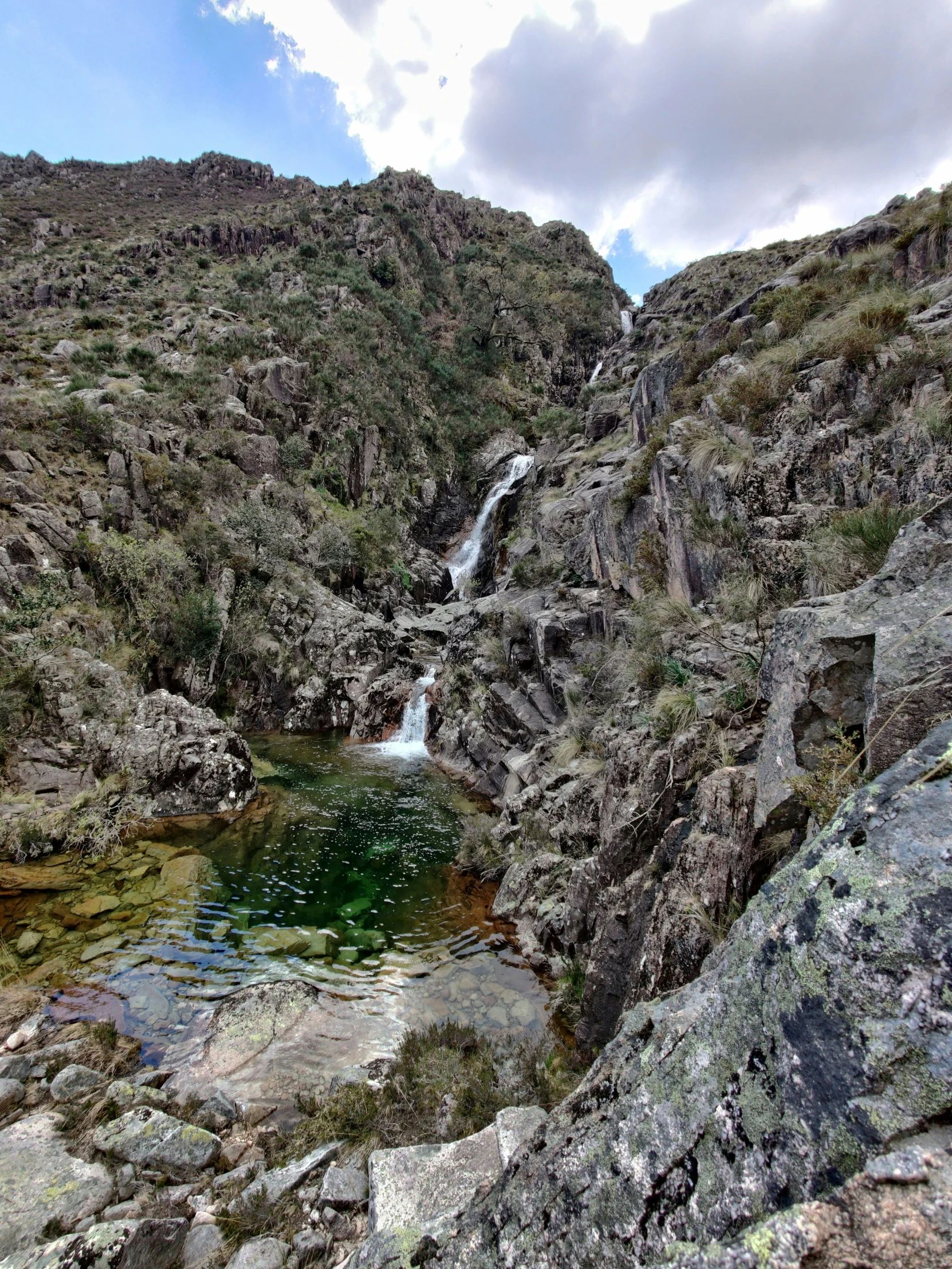 there is a green pool near a steep cliff