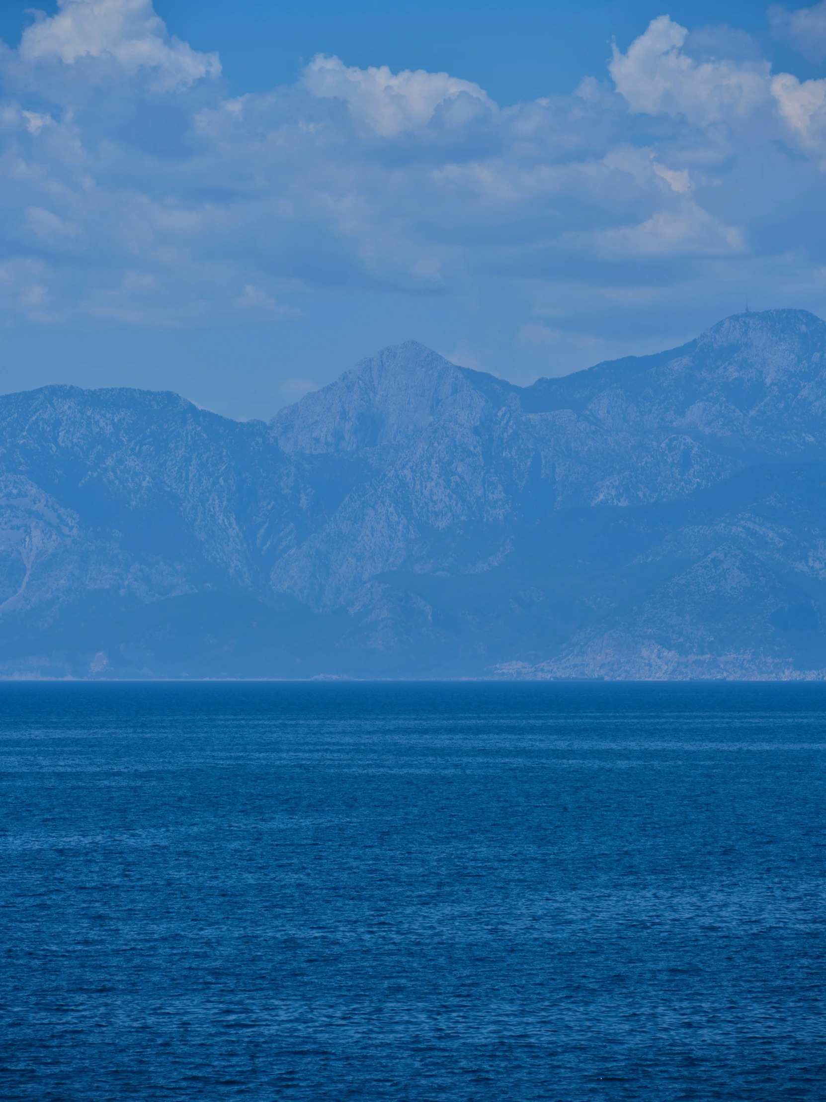 a sailboat is on the ocean with mountains in the background