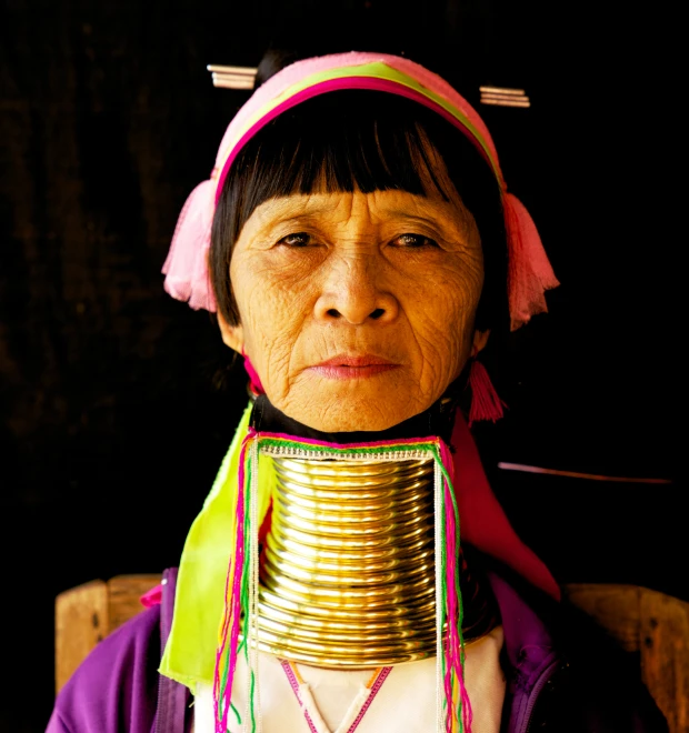 an old woman is wearing a neck ring and necklace