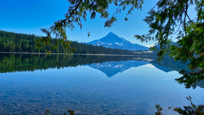 a view of the mountains and trees are reflected in the water