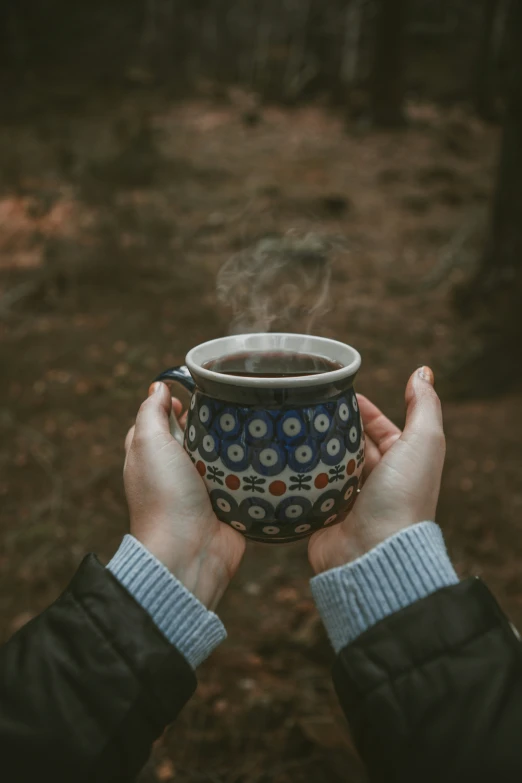 the person is holding a cup full of steaming tea