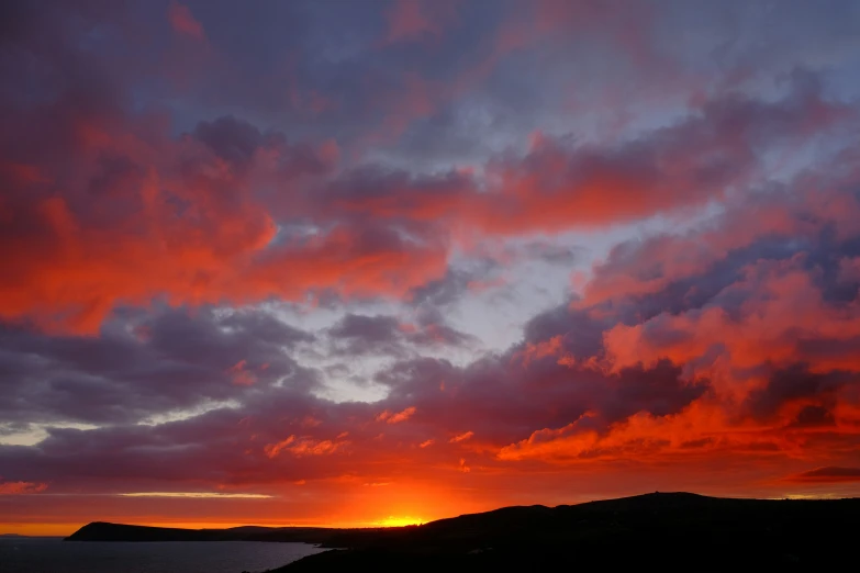 a sunset is seen from the shore as dark clouds move over